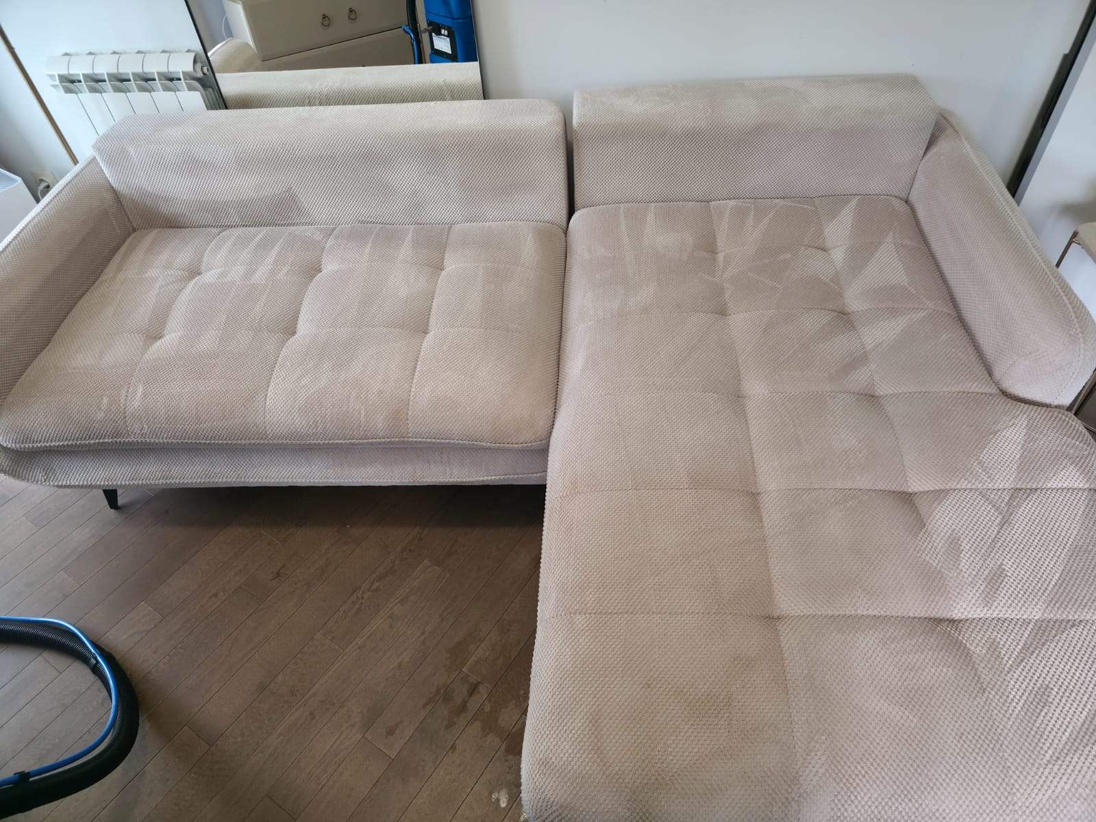 Light beige fabric sectional sofa with tufted cushions on wooden floor.